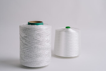 Two spools of white fiberglass thread, one with a green core and one with a green tip, displayed against a plain white background...