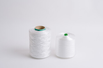 Two spools of white fiberglass thread with green cores, placed side by side on a white background, showcasing different sizes.