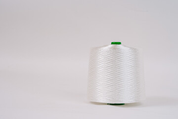A spool of white fiberglass thread with a green top, displayed against a plain white background, showcasing the texture and weave of the material...