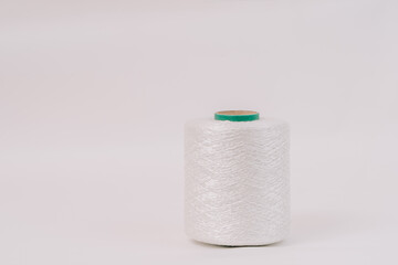 A spool of white braided fiberglass thread with a green core, isolated on a white background. Industrial material concept with copy space.