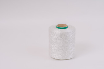 A spool of white braided fiberglass thread with a green core, isolated on a white background. Industrial material concept with copy space.