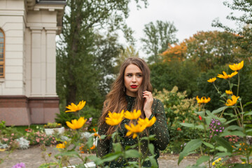 Attractive woman posing in yellow autumn flowers in park outdoor