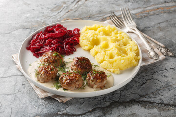 Traditional meatballs with creamy sauce garnished with mashed potatoes and beets close-up in a...