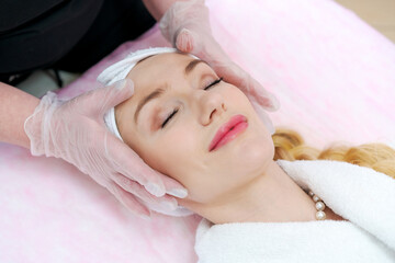 A woman is getting a facial treatment with a woman assisting her