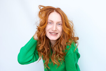 A woman with red hair is smiling and wearing a green sweater