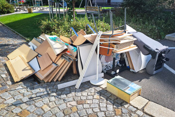 A heap of assorted discarded household items and furniture piled up on a cobblestone street,...