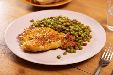 Fried boneless skinless chicken leg with green peas for garnish on plate