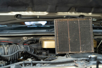 Fototapeta premium Old air filter on the hood of a car. Close-up.The old car air filter has expired and must be replaced.
