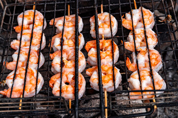 Grilling shrimp over an open fire in the woods.