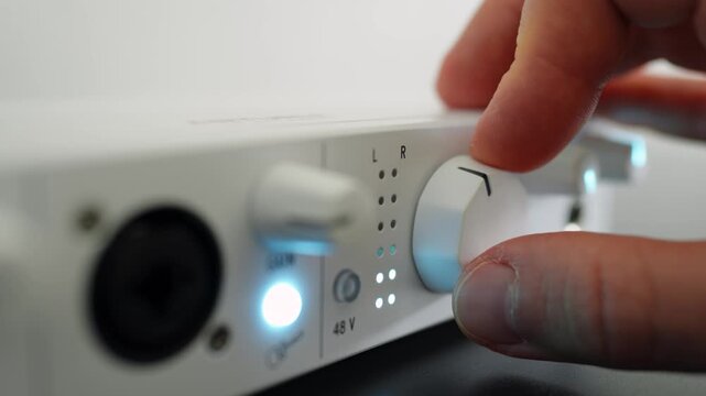 Man turning a volume knob on an audio interface. Close up