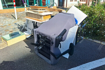 Assorted discarded items including overturned office chair, wooden boards, and home furnishings...
