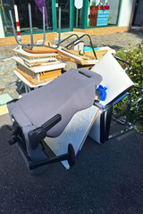 A heap of assorted discarded household items and furniture piled up on a cobblestone street, depicting a bulk waste collection day in an urban environment. Vertical picture.