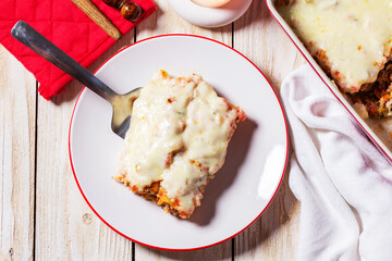 Cannellone with meat filling, tomato sauce and cheese on a light wooden table.