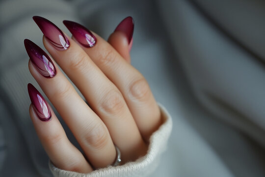 Main f&eacute;minine avec manucure &eacute;l&eacute;gante, ongles longs en amande avec d&eacute;grad&eacute; de couleurs roses et violettes, d&eacute;coration subtile d'une pierre pr&eacute;cieuse, moderne, styletto, gel transparent, prune