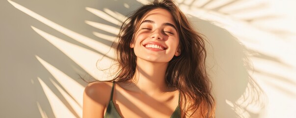 A joyful woman smiles brightly while sunlight casts playful shadows on her face, embodying happiness and warmth.