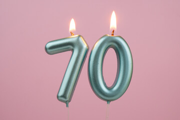 Burning blue birthday candles on pink background, number 70