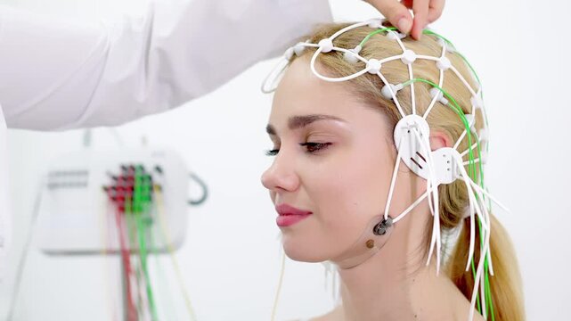 A doctor places EEG sensors on a young patient's head for brain testing in a medical center. Ideal for showcasing advanced diagnostics and professional healthcare settings.
