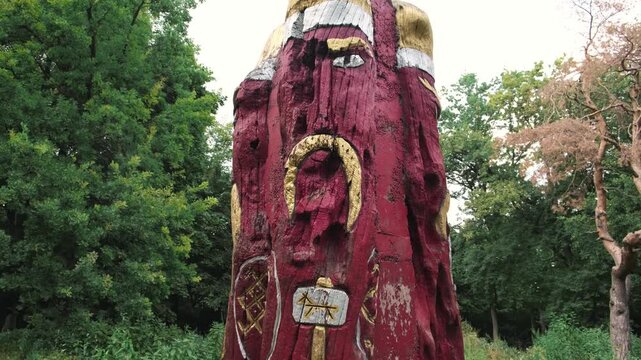 Ancient Slavic pagan deity idol in the forest, wooden sculpture with red and gold accents.