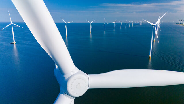 Wind turbines gracefully harnessing renewable energy in the serene waters of the Netherlands, promoting sustainability and innovation. drone top view at a windmill park in the ocean