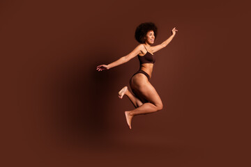Obraz premium Full length photo of excited funky lady underwear jumping enjoying girls power isolated brown color background