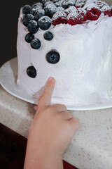 a little kid touching the cream on the cake
