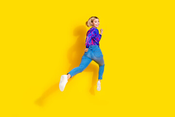 Full size photo of pretty young girl run fast back view turn around wear trendy colorful blue outfit isolated on yellow color background