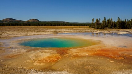 Vibrant hot spring in Yellowstone National Park surrounded by a barren landscape in Wyoming, USA