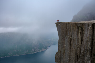 Daring Explorers Stand on Preikestolen Cliff Overlooking the Fjords of Norway