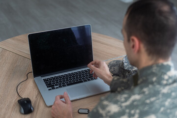 Portrait of young army soldier with a laptop 