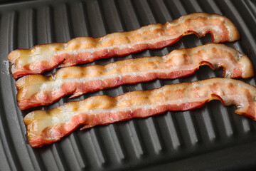 Slices of bacon on grill, closeup view