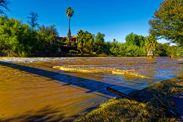 Flooded river that's burst it's banks with destroyed fence following heavy rains in Oudtshoorn,...