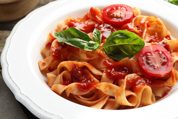 Delicious pasta with tomato sauce and basil on table, closeup