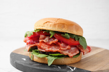 Delicious burger with bacon, tomato and greens on light background, closeup