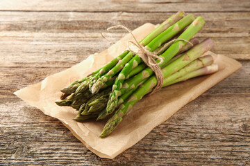 Bunch of fresh green asparagus stems on wooden table, closeup