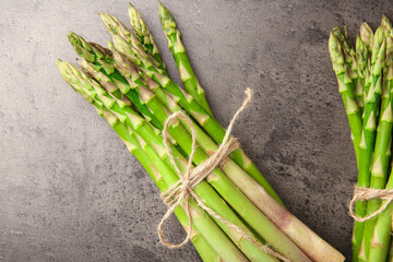 Fresh green asparagus stems on grey textured table, flat lay