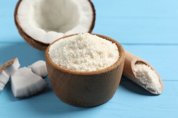 Fresh coconut flour in bowl, scoop and nut on light blue wooden table