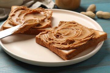 Tasty sandwiches with peanut butter on light blue wooden table, closeup