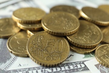 Many euro coins on dollar banknotes, closeup