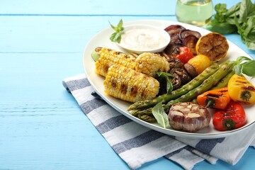 Delicious grilled vegetables on light blue wooden table, closeup. Space for text