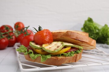 Tasty sandwich with grilled vegetables on white tiled table, closeup