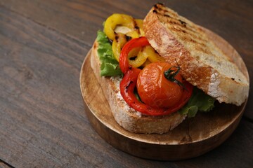 Tasty sandwich with grilled vegetables on wooden table, closeup. Space for text