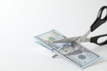 Budgeting. Cutting dollar banknotes with scissors on white background, closeup. Space for text