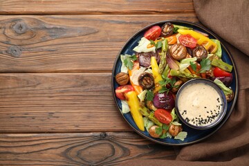 Delicious salad with grilled vegetables and sauce on wooden table, top view. Space for text