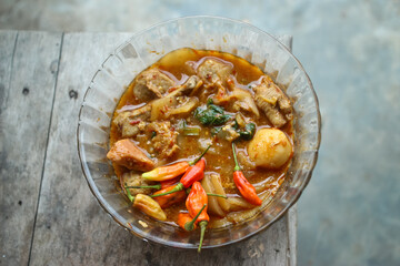 Seblak is a typical Indonesian dish with a savory and spicy taste. Made from wet crackers cooked with vegetables, sausage, eggs. a bowl of seblak on a wooden table.