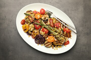 Delicious salad with grilled vegetables served on gray textured table, top view