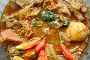 Seblak is a typical Indonesian dish with a savory and spicy taste. Made from wet crackers cooked with vegetables, sausage, eggs. a bowl of seblak on a wooden table.