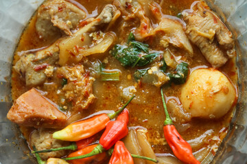 Seblak is a typical Indonesian dish with a savory and spicy taste. Made from wet crackers cooked with vegetables, sausage, eggs. a bowl of seblak on a wooden table.