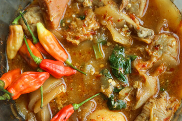 Seblak is a typical Indonesian dish with a savory and spicy taste. Made from wet crackers cooked with vegetables, sausage, eggs. a bowl of seblak on a wooden table.