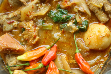 Seblak is a typical Indonesian dish with a savory and spicy taste. Made from wet crackers cooked with vegetables, sausage, eggs. a bowl of seblak on a wooden table.