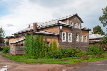 Unpainted wooden house with mezzanine in northern russian village, decorated with climbing plants
